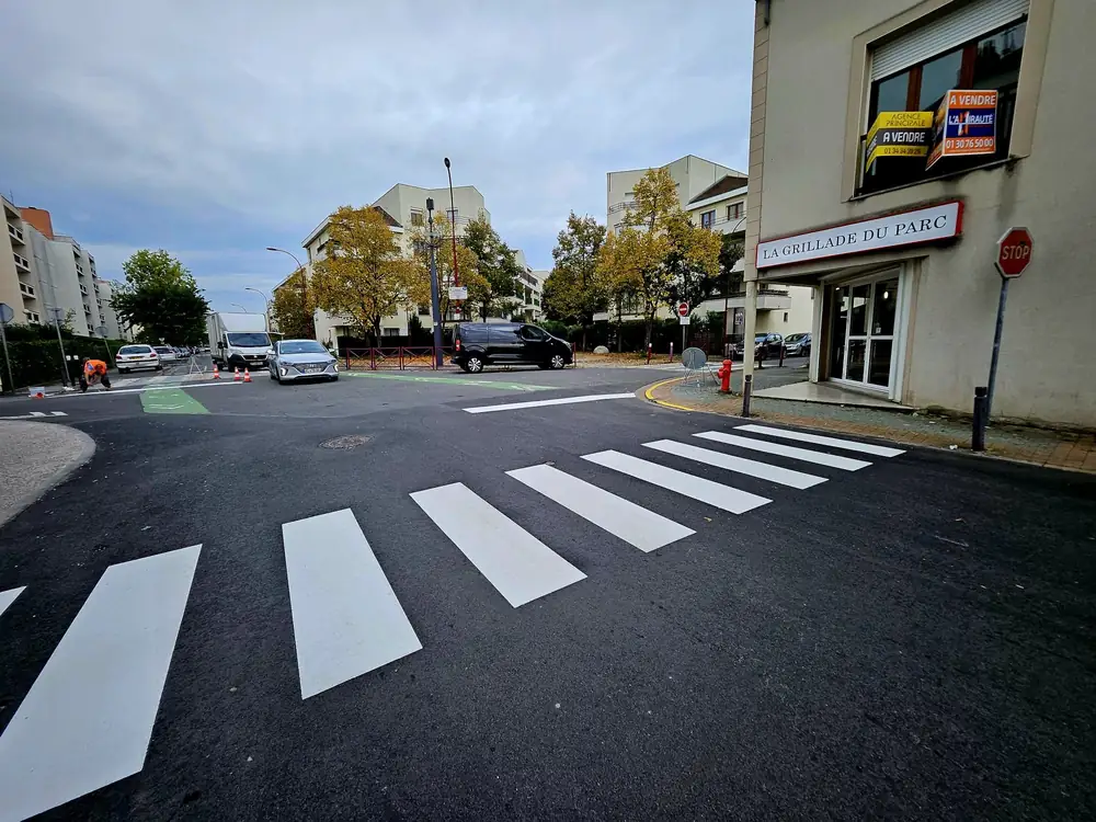 Passage piéton en carrefour — Bandes blanches sur enrobé neuf.