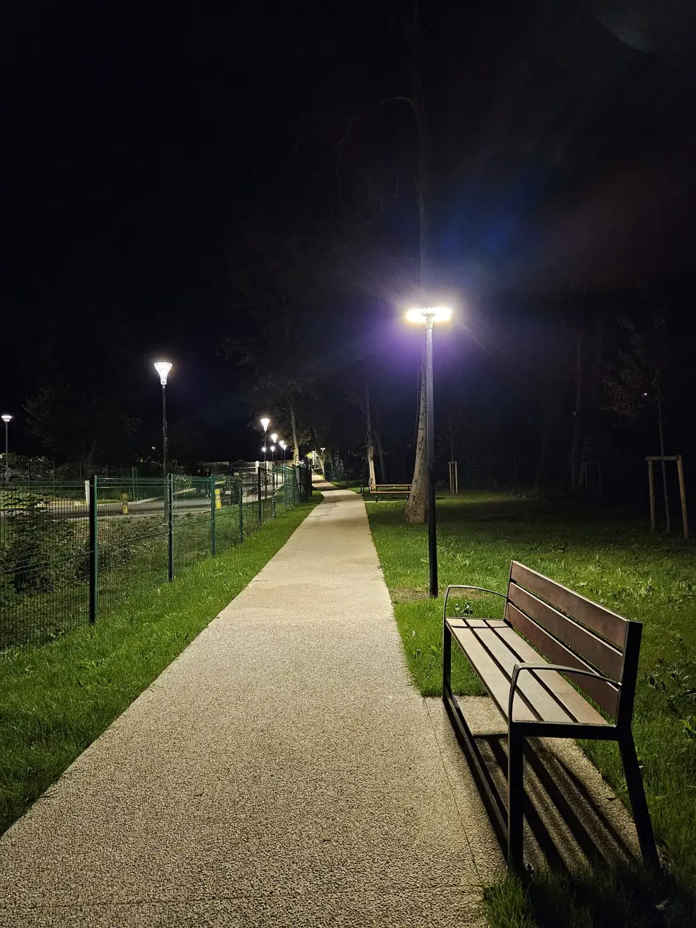 Allée de parc éclairée — Mâts LED, banc et cheminement stabilisé.