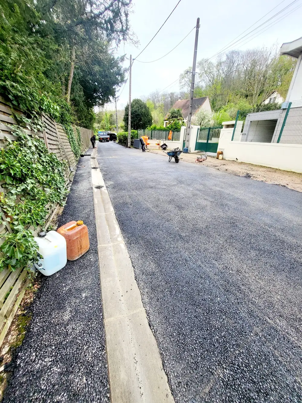 Rue réhabilitée — Caniveau béton et chaussée en enrobé neuf.