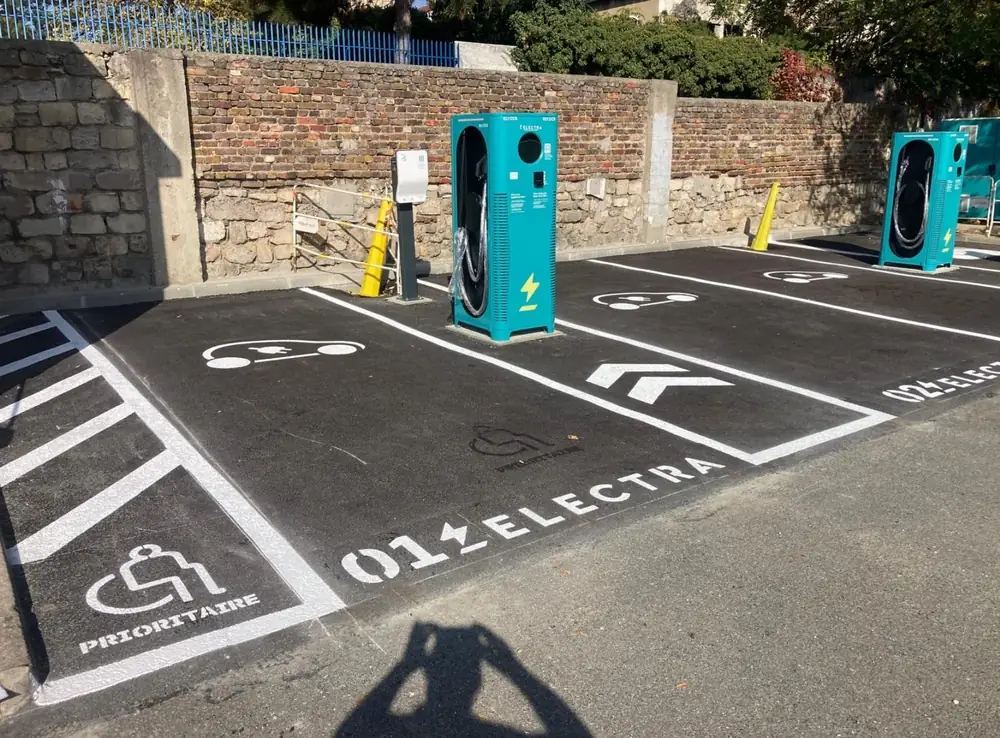 Places de recharge — Pictogrammes véhicule électrique et place PMR prioritaire.