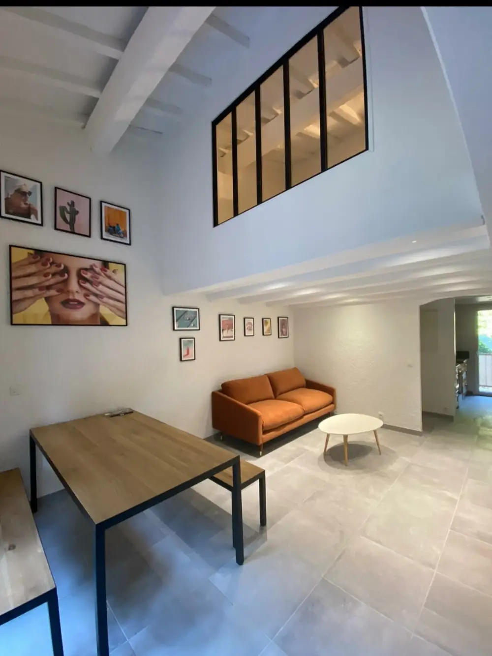 Séjour en duplex — Verrière d’atelier, sol grand format, murs blancs.